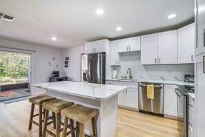 A modern kitchen with white cabinets, a stainless steel refrigerator, and a central island with stools.