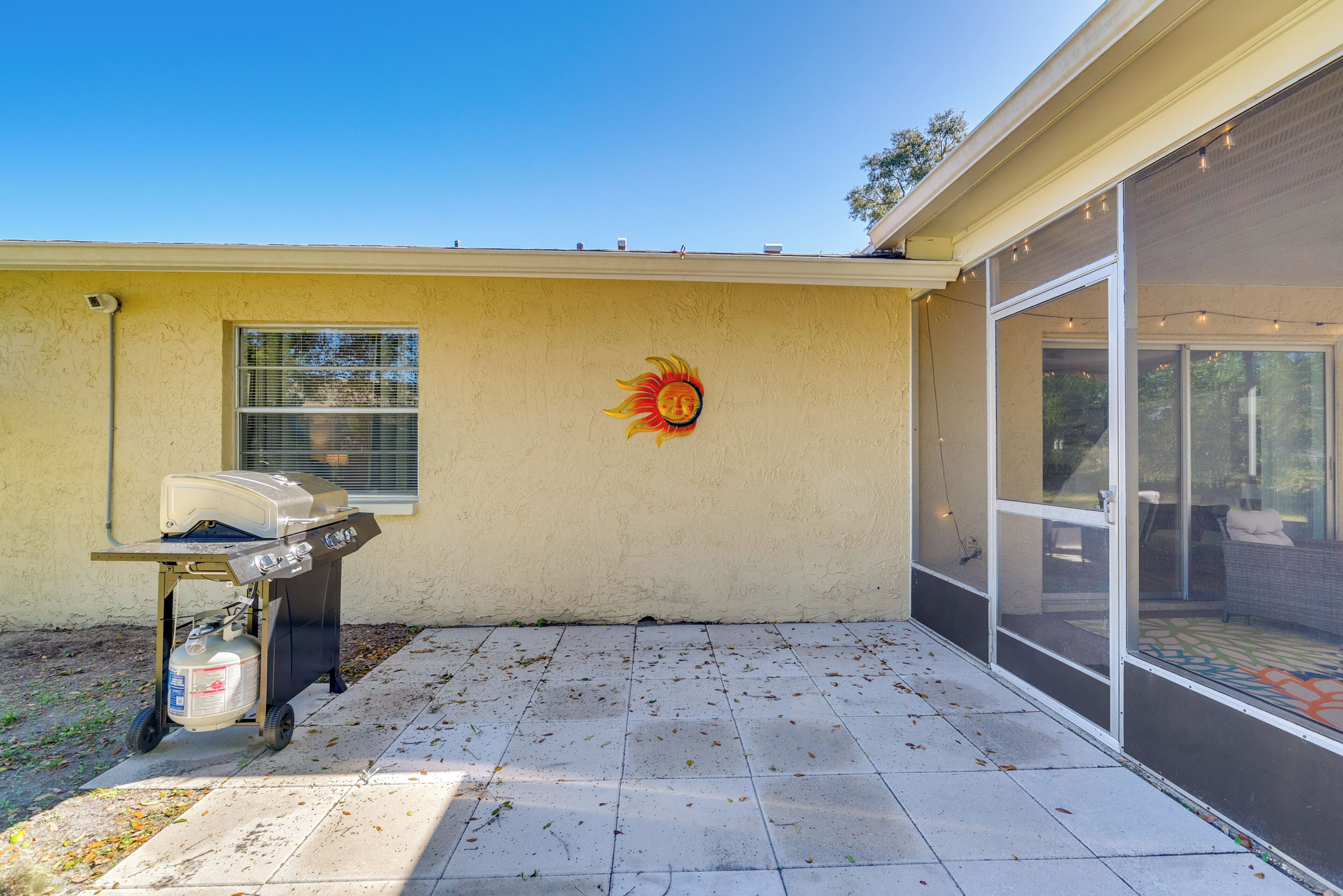 A patio with a grill and a sun mural on a house wall.