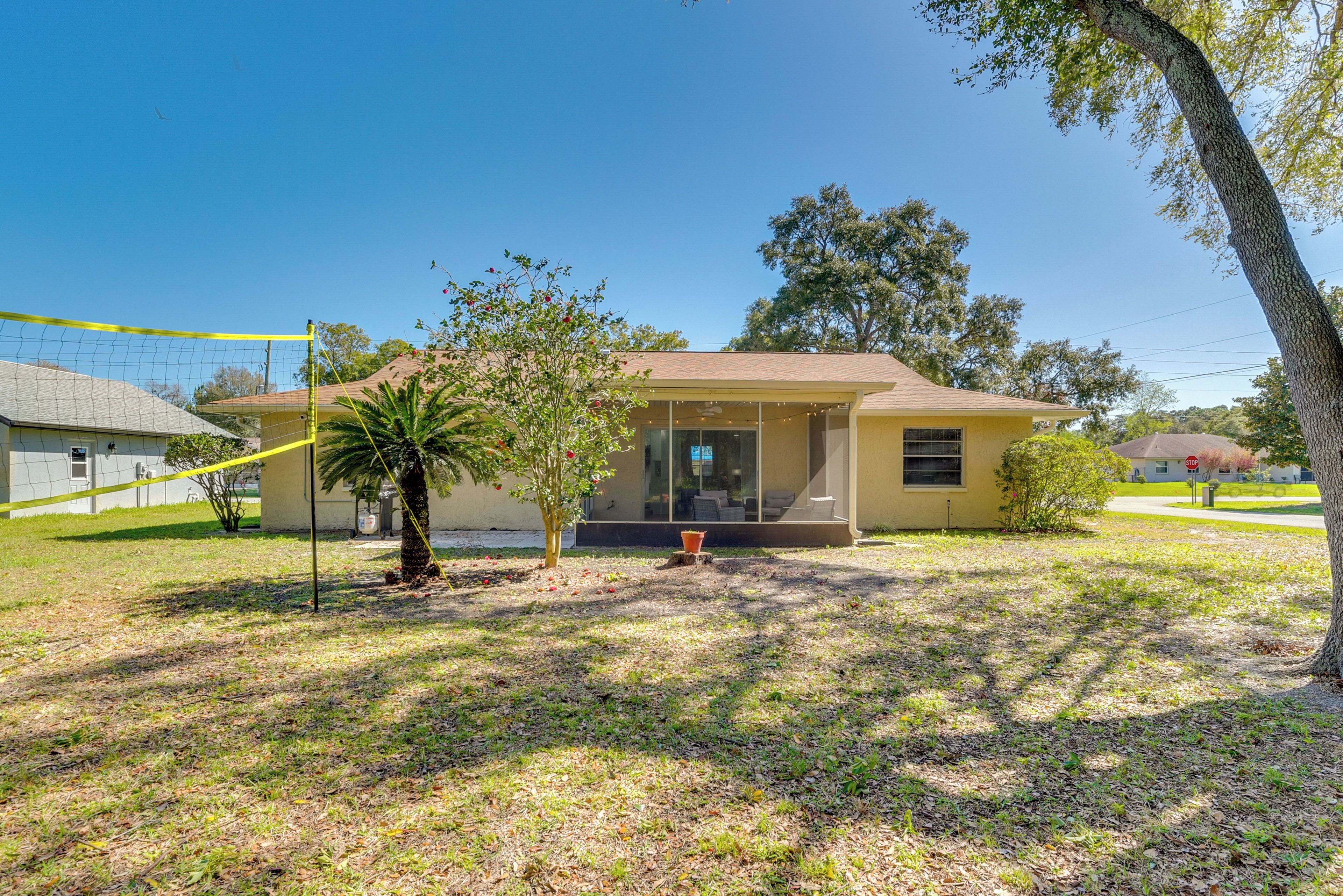 A single-story house with a front porch, a small tree, and a volleyball net in the yard.