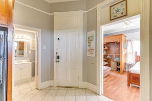A hallway leading to a bedroom with a wooden floor, a white door, and a ceiling fan.