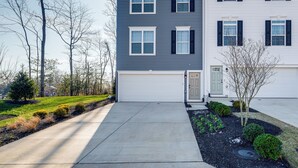 A two-story residential building with a garage, a driveway, and a landscaped front yard with shrubs and a small tree. - 30 Mi to Downtown DC: Charming Dale City Townhome! (Woodbridge)