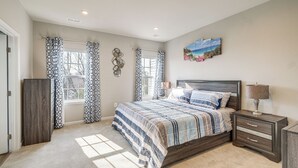 A bedroom with a large bed, a nightstand, a dresser, and a window with patterned curtains. - 30 Mi to Downtown DC: Charming Dale City Townhome! (Woodbridge)