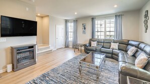 A modern living room with a sectional sofa, a flat-screen TV, and a fireplace. - 30 Mi to Downtown DC: Charming Dale City Townhome! (Woodbridge)