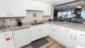 Una cocina moderna con armarios blancos, encimera de granito y vistas al balcón.