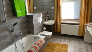 Et moderne badeværelse med badekar, brusebad og håndvask.