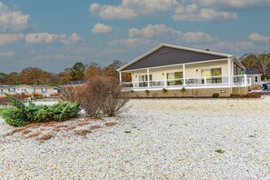 A two-story house with a covered porch and a gravel driveway. - Stunning-waterfront, beach, pools, family fun (Long Neck)