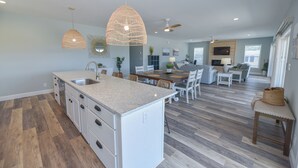 A spacious kitchen with a large island, pendant lighting, and a dining area with a wooden table and chairs.