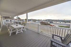 A covered deck with white furniture and a view of a marina. - Stunning-waterfront, beach, pools, family fun (Long Neck)