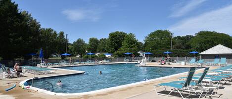 A swimming pool area with multiple pools, lounge chairs, and umbrellas.