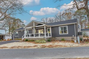 A two-story house with a covered porch, a driveway, and a well-maintained lawn.