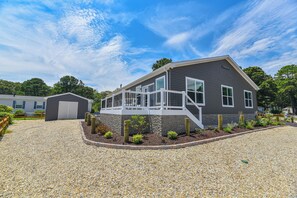 A modern two-story house with a covered porch, a gravel driveway, and a small garden area.