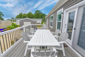 A deck with a white table and chairs, a railing, and a door with a glass panel.