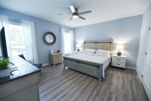 A bedroom with a bed, bedside tables, a ceiling fan, and a window with curtains.