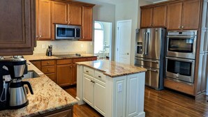 Una cucina moderna con mobili in legno, elettrodomestici in acciaio inossidabile e un piano di lavoro in granito.