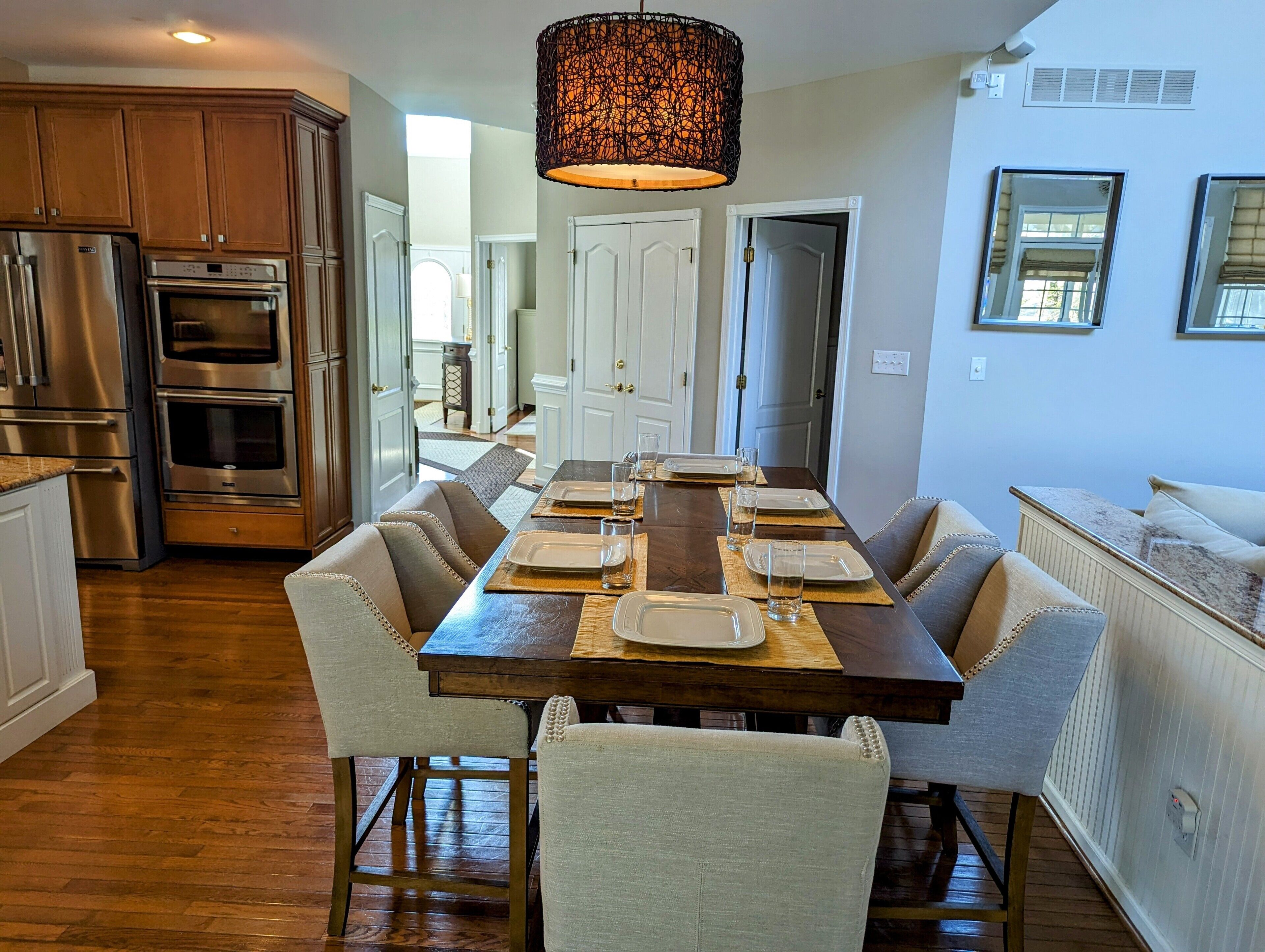 A dining area with a wooden table set for four, surrounded by upholstered chairs.