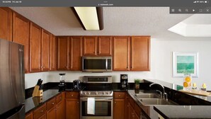 Una cocina moderna con armarios de madera, electrodomésticos de acero inoxidable y una encimera negra.