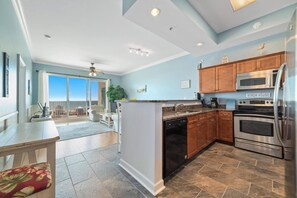 A spacious kitchen with modern appliances, a dining area with a view, and a large sliding glass door leading to a balcony. - Top-Floor 2BR/2BA Condo with Stunning Gulf Views | Sleeps 6 (Gulf Shores)