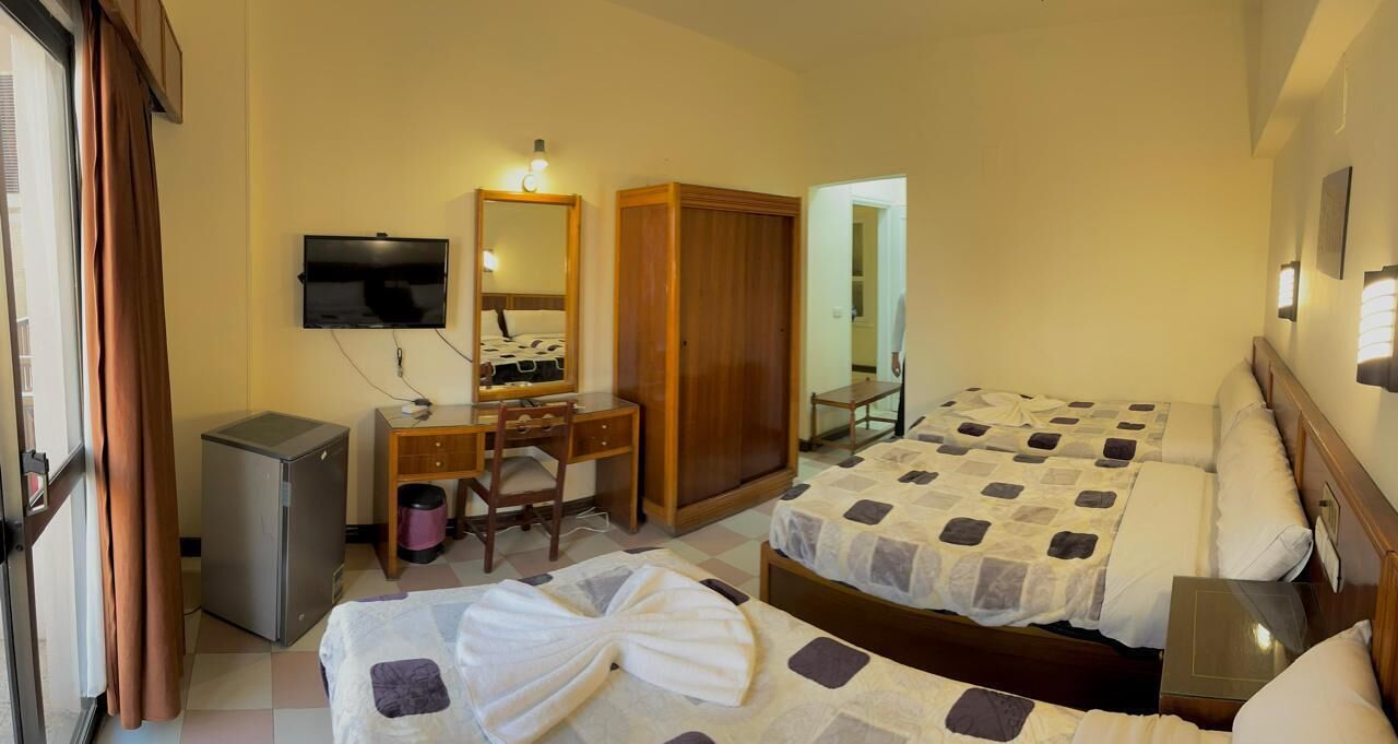 Habitació d'hotel amb dos llits, un escriptori amb cadira, televisió i un armari.