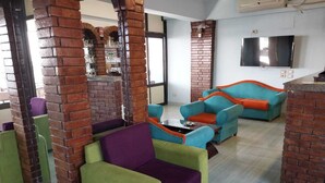 Een moderne lounge met bakstenen details, kleurrijke zitplaatsen en een flatscreen televisie.