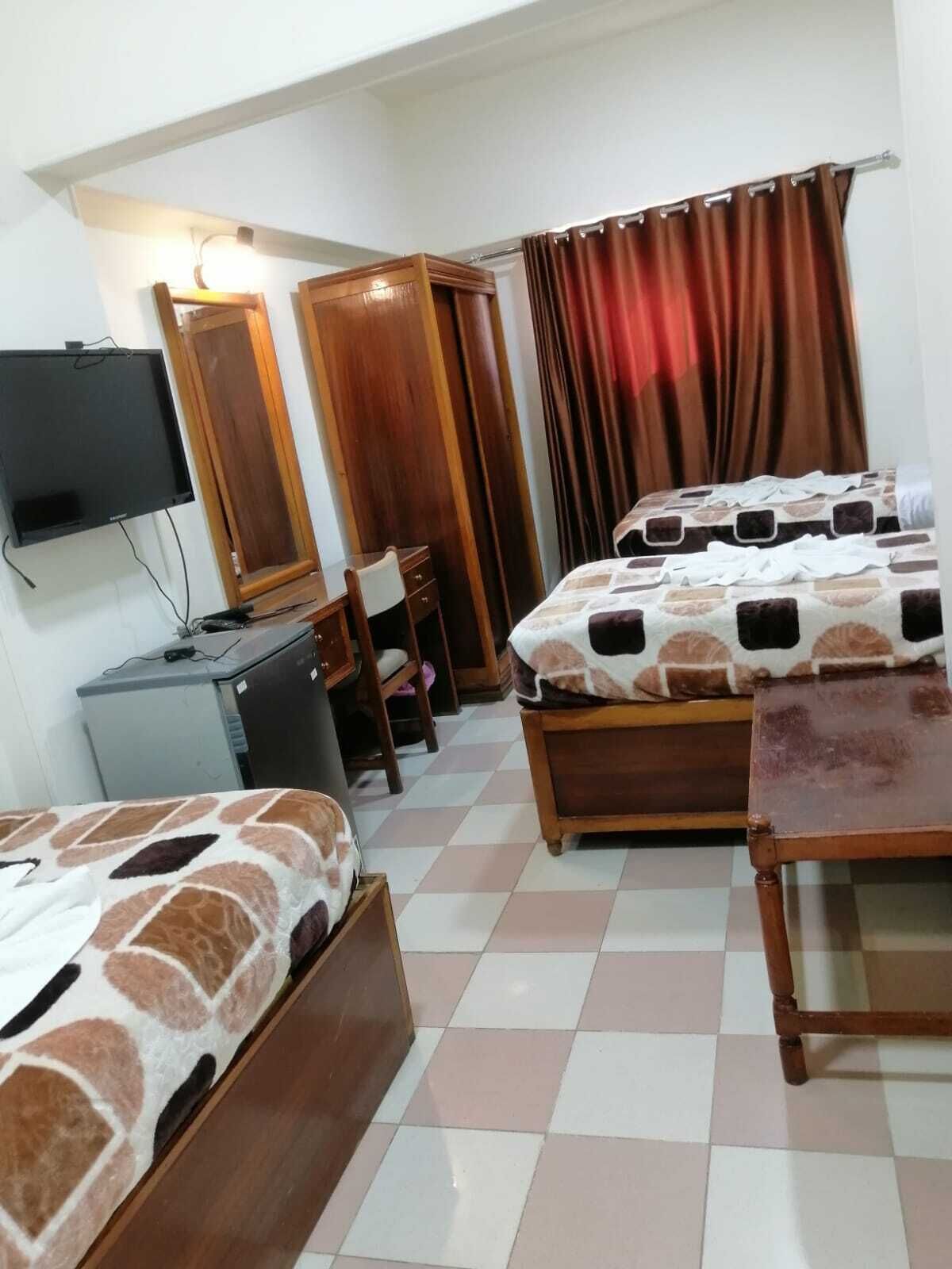A hotel room with two beds, a desk, a television, and a wardrobe.