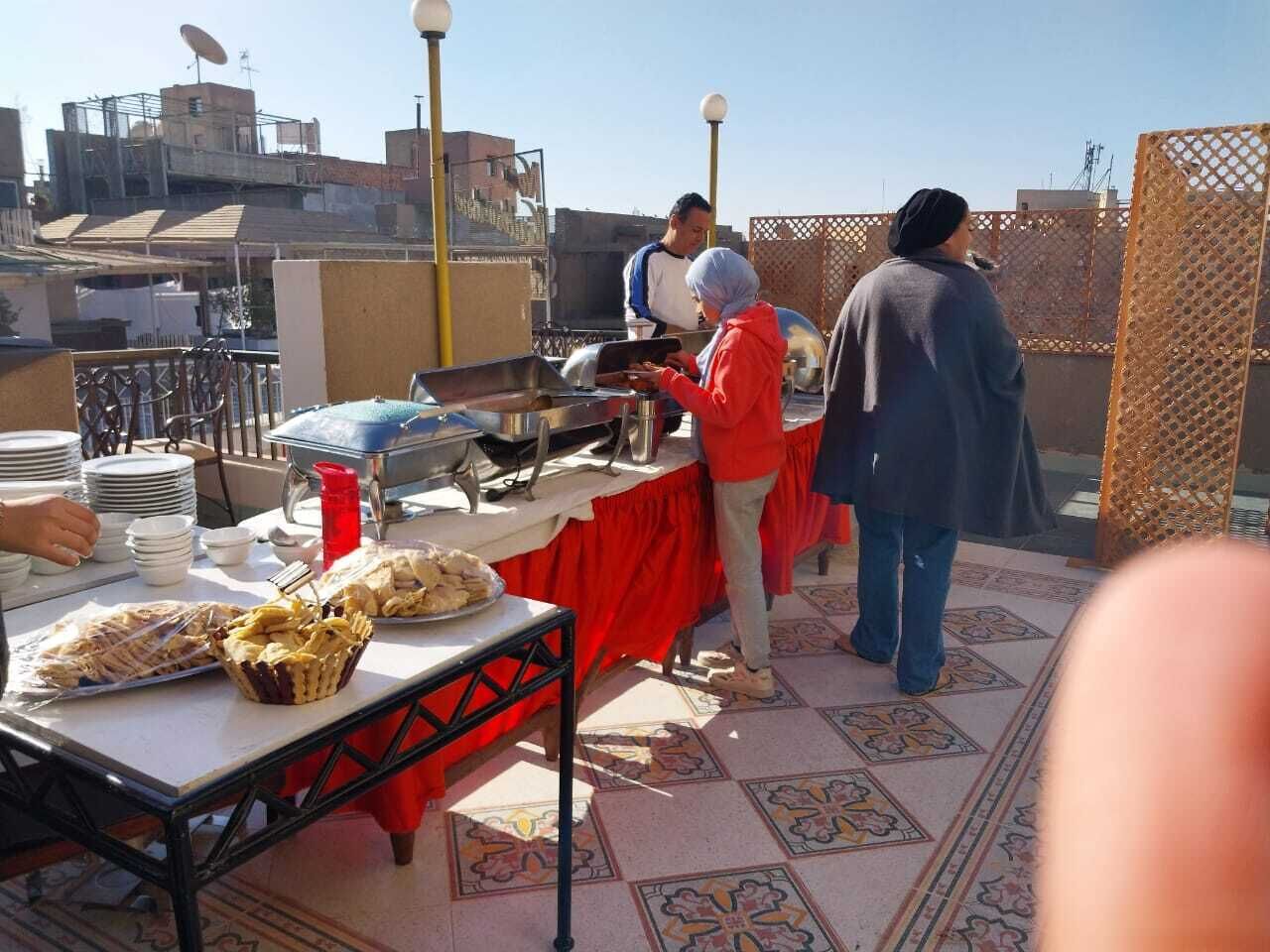 Un espacio para comer en la azotea con un sistema de buffet, que incluye una mesa con comida y una persona sirviendo.