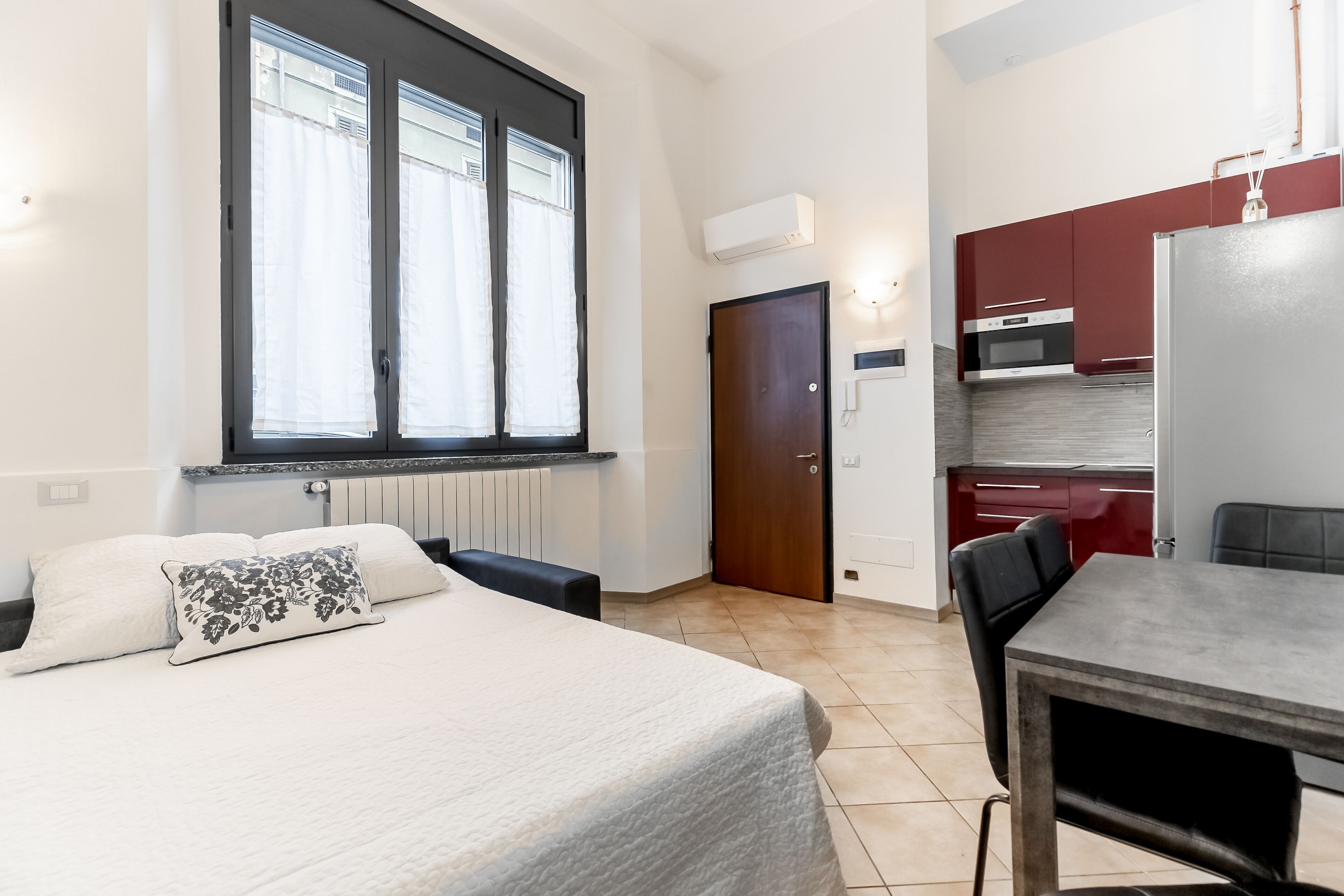 A bedroom with a bed, a bedside table, and a window with curtains.