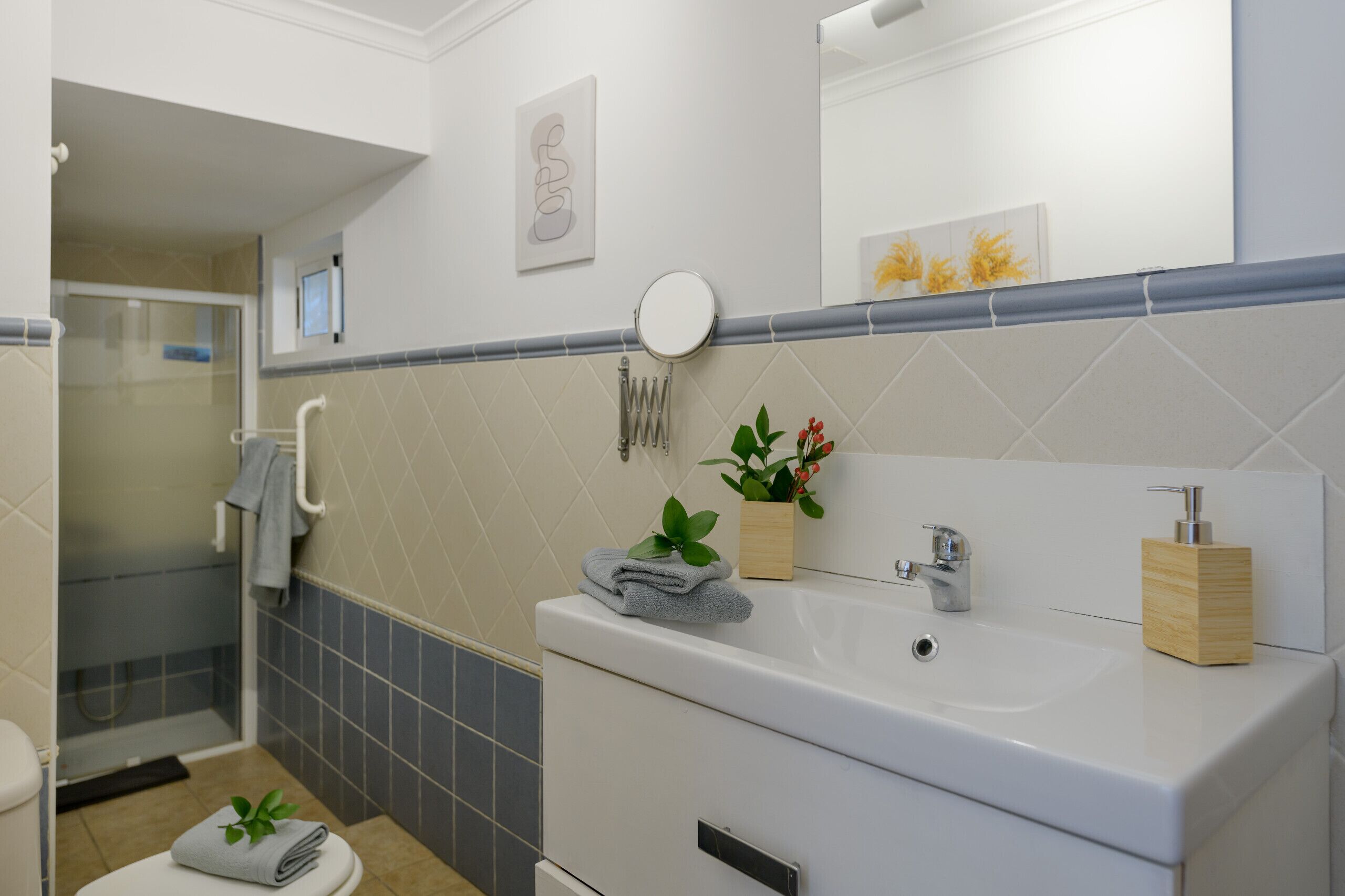 Een moderne badkamer met een wit wastafelmeubel, een spiegel en een douchehoek.