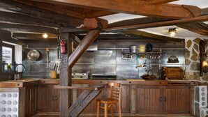 Eine rustikale Küche mit Holzbalken, einem Holzhocker und einer Steinwand.