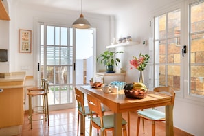 Une cuisine lumineuse avec une table en bois, des chaises et une fenêtre donnant sur l’extérieur.