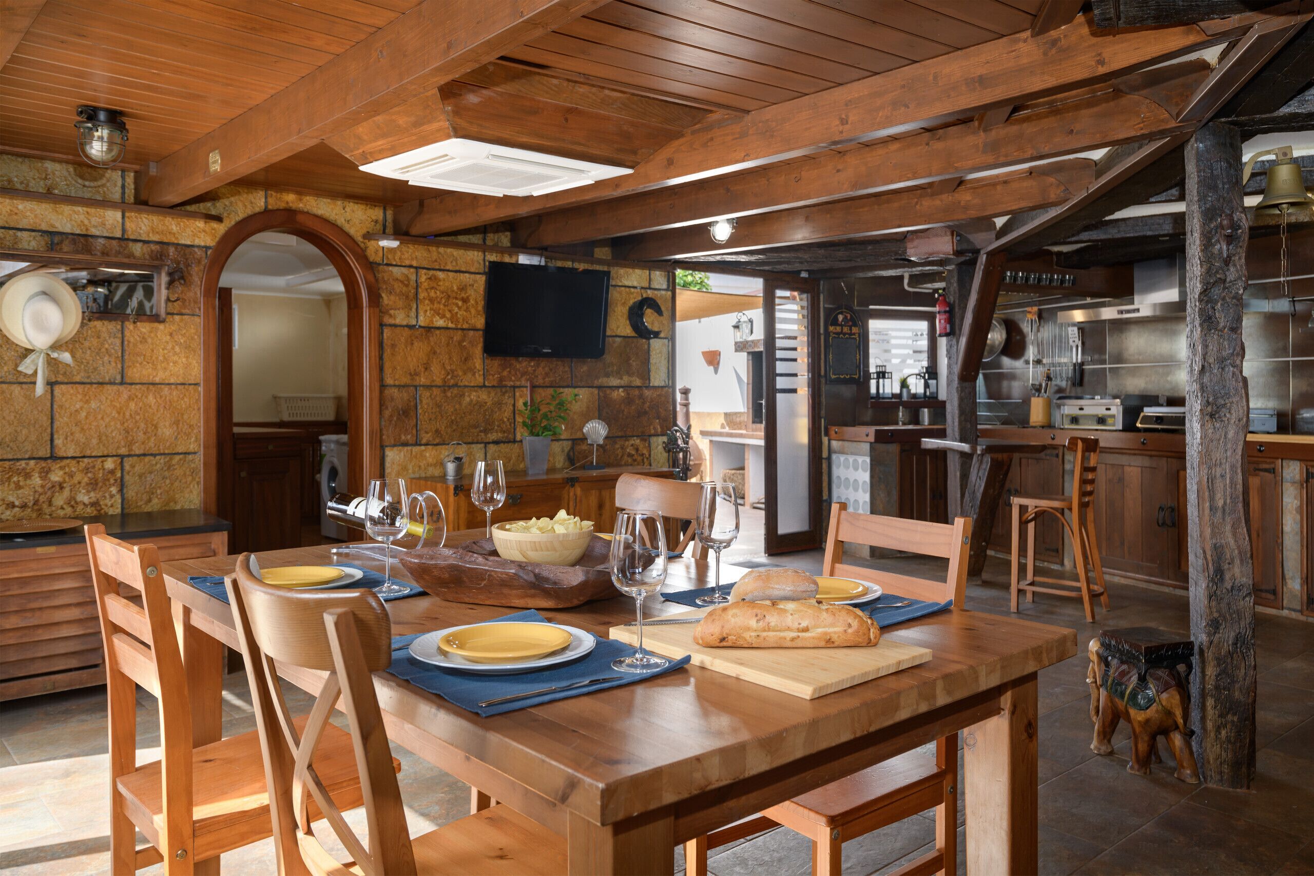 A wooden dining table set with plates, glasses, and a loaf of bread.