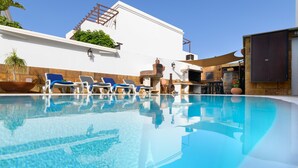 Ein klares Schwimmbecken mit Liegestühlen und Grillplatz.