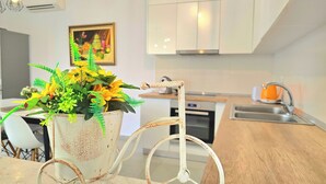 A modern kitchen with white cabinets, a stainless steel sink, and a vintage bicycle chair. - Lalzit Bay Dream Villa (Ishëm)