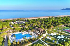 An aerial view of a resort with a large swimming pool, lush greenery, and a beach area. - Lalzit Bay Dream Villa (Ishëm)