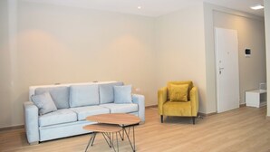 Een moderne woonkamer met een lichtblauwe bank, een klein houten tafeltje en een gele fauteuil.