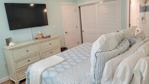 Un dormitorio con cama, cómoda, televisor y armario.