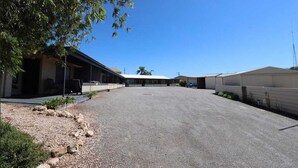 A commercial building with a covered parking area, outdoor seating, and a gravel driveway.