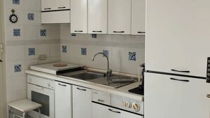 Une cuisine de taille réduite avec des meubles blancs, un évier et un petit plan de travail.