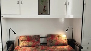 Une chambre à coucher comprenant un lit, deux tables de chevet, un miroir et une armoire.