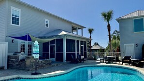 Une maison avec une piscine, un patio couvert et une cheminée en pierre.