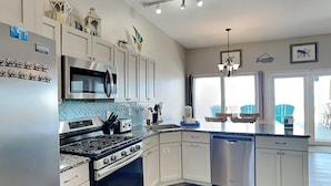 A modern kitchen with stainless steel appliances, white cabinetry, and a blue backsplash. - Charline Beachside Villa | Gulf Front Luxury (Panama City Beach)