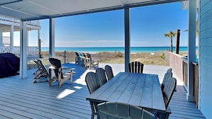 A covered deck with a view of the beach, featuring a table and chairs. - Charline Beachside Villa | Gulf Front Luxury (Panama City Beach)