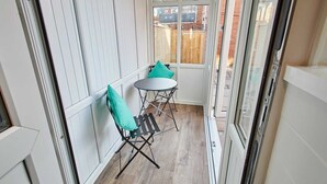 A narrow balcony with a small table and two chairs, a view of a wooden fence and buildings in the background. - Host & Stay | Station View (Saltburn-by-the-Sea)
