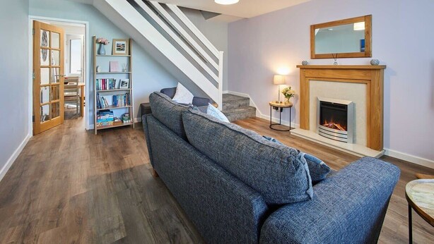 A living room with a blue sofa, a fireplace, a bookshelf, and a staircase. - Host & Stay | Station View (Saltburn-by-the-Sea)