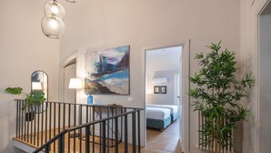 En modern inredning med en trappa, en tavla, en krukväxt och en säng i bakgrunden.