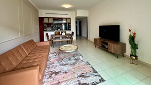 Un soggiorno con divano, tavolino, televisore e zona pranzo con sedie e tavolo.