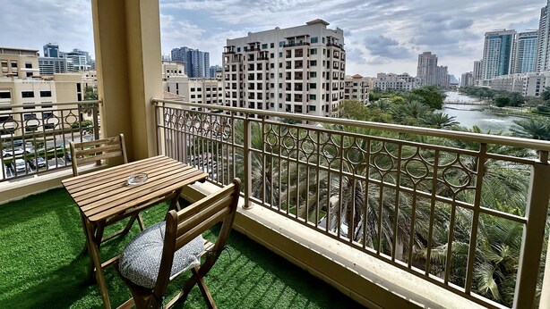 Un balcone con tavolo e sedie di legno, affacciato su un fiume e sullo skyline della città.