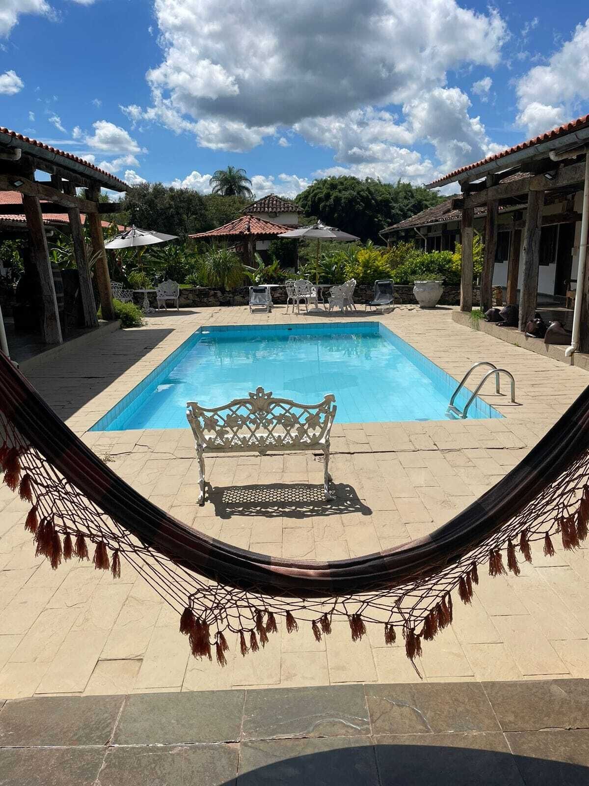 A pool with a bench in the center, surrounded by lounge chairs and umbrellas.
