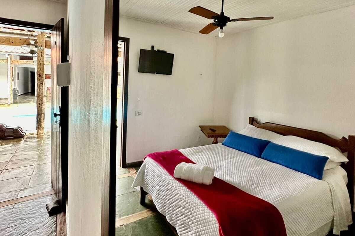 A bedroom with a bed, a ceiling fan, and a television on the wall.