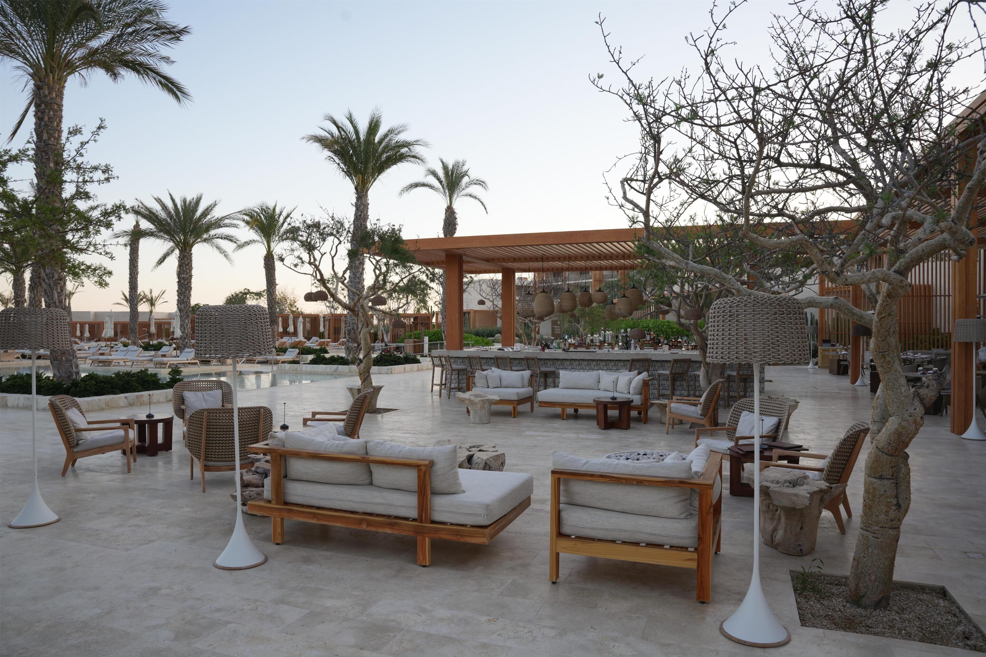 Un espace aménagé au bord de la piscine, avec des chaises longues, une pergola et un coin bar.