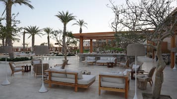 Un espace aménagé au bord de la piscine, avec des chaises longues, une pergola et un coin bar.